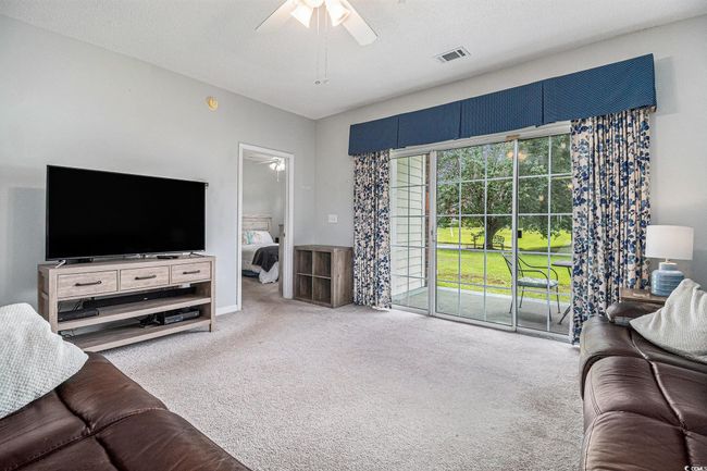 Living area featuring ceiling fan, carpet floors, entrance to patio, with storage. | Image 8