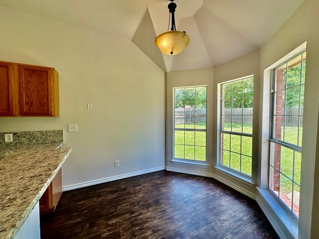 Unfurnished dining area with healthy amount of natural light, dark wood-style floors, and vaulted ceiling | Image 4