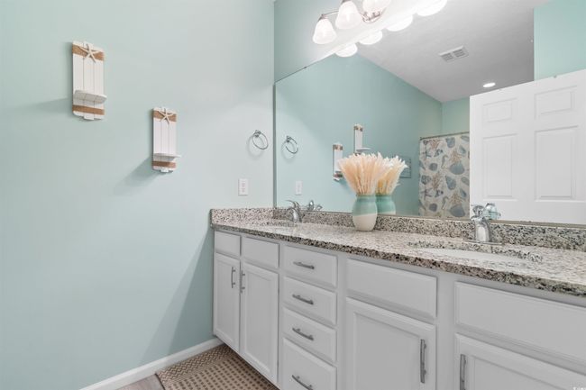 Bathroom with double vanity, a shower with shower curtain, and baseboards | Image 16
