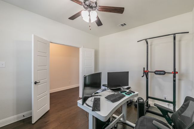 Office area with visible vents, baseboards, dark wood-type flooring, and a ceiling fan | Image 9