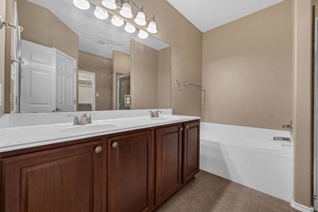 The private primary suite boasts tall ceilings, a ceiling fan, and a luxurious en-suite bathroom complete with a double vanity, garden soaking tub, separate shower, and a large walk-in closet. | Image 17