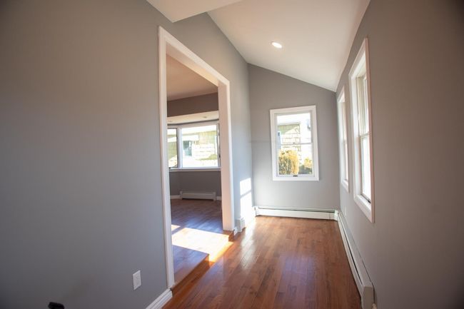 Hallway with dark hardwood / wood-style flooring, baseboard heating, and lofted ceiling | Image 29