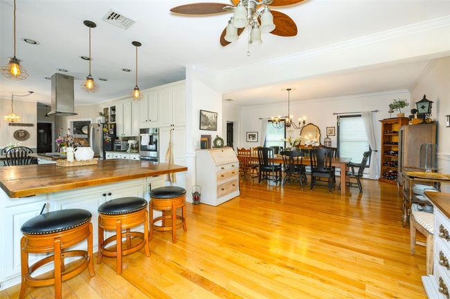 Kitchen with wood counters, a ceiling fan, light wood-type flooring, island exhaust hood, and appliances with stainless steel finishes | Image 11