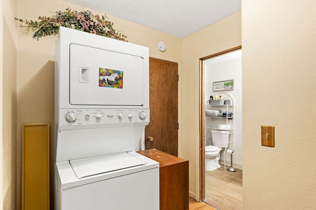 Separate apartment above garage Washroom with stacked washer and dryer, a textured ceiling, light wood-style flooring, and laundry area | Image 73