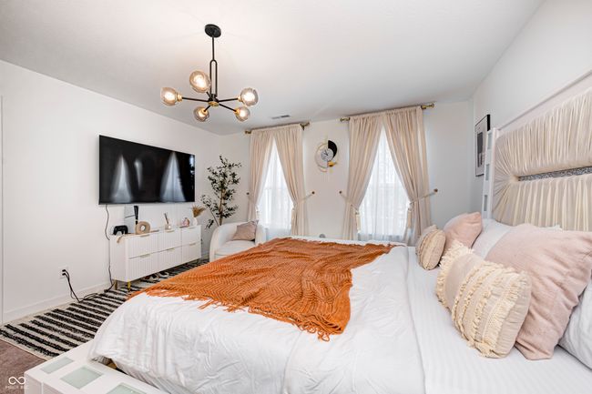carpeted bedroom featuring a notable chandelier and baseboards | Image 25