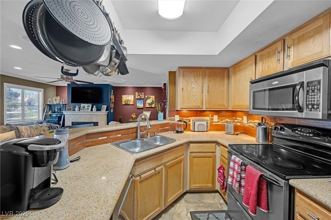 Kitchen featuring a sink, a fireplace, black electric range oven, open floor plan, and stainless steel microwave | Image 11