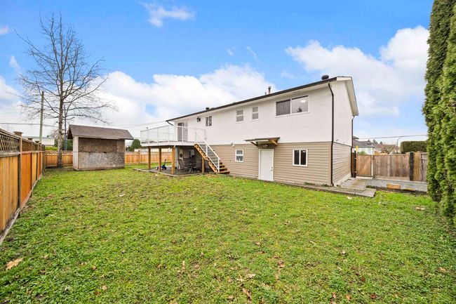 Back of house featuring an outbuilding, stairway, a fenced backyard, a storage unit, and a lawn | Image 25