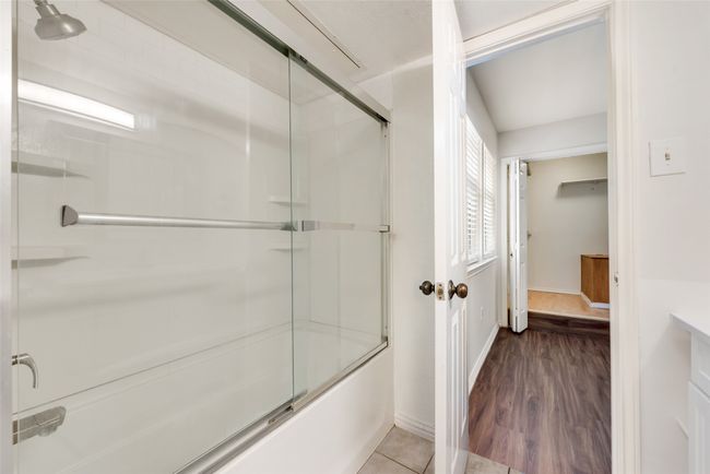 Bathroom with bath / shower combo with glass door, with tile floors and vanity. | Image 21
