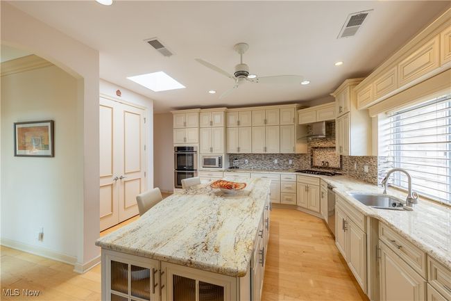 Kitchen with skylight, features granite countertops, large center island, plentiful cabinet space, pantry, stainless steel appliances, high ceilings and private catering entrance. | Image 10