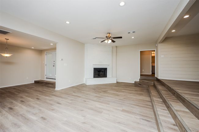 Unfurnished living room with recessed lighting, ceiling fan, a brick fireplace, and wood finished floors | Image 5