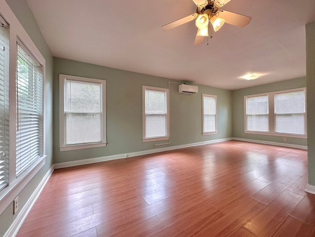 Living room with an AC wall unit, wood finished floors, and a ceiling fan | Image 4