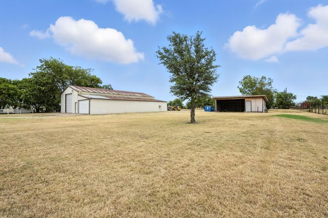 View of green lawn featuring a pole building, a detached garage, and an outbuilding | Image 4