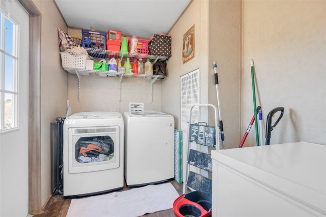 Laundry room featuring washer and clothes dryer, laundry area, and wood finished floors | Image 24