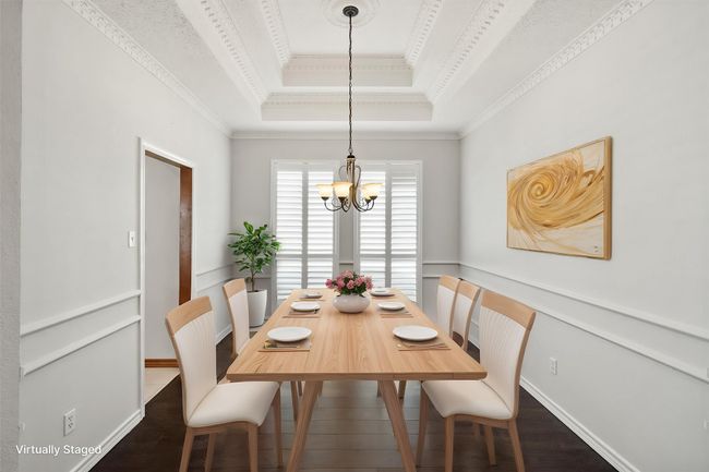 This goreous formal dining area has engineered wood floors, double chair railing, a wall of windows with plantation shutters and a tray ceiling accented with custom crown molding. | Image 16