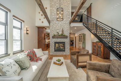 Great room with double sided fireplace, custom metal railing and hand hewn beams | Image 2