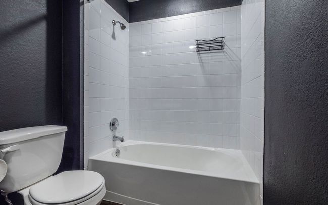 Bathroom featuring a textured wall and bathtub / shower combination | Image 18