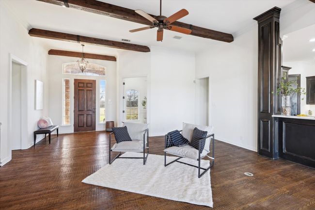 Foyer entrance featuring beam ceiling, dark wood finished floors, a ceiling fan, a chandelier, and baseboards | Image 12