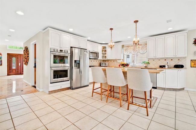 Kitchen featuring appliances with stainless steel finishes, recessed lighting, tasteful backsplash, glass insert cabinets, and white cabinetry | Image 15