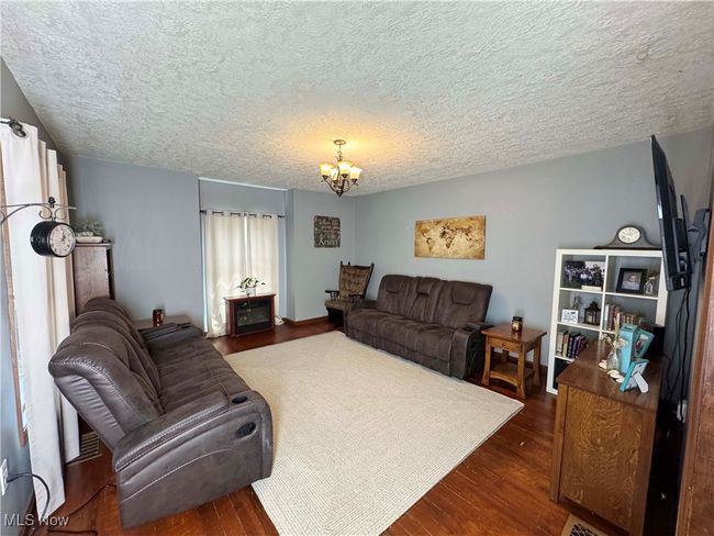 Living room featuring a chandelier, dark wood-type flooring, and a textured ceiling | Image 11