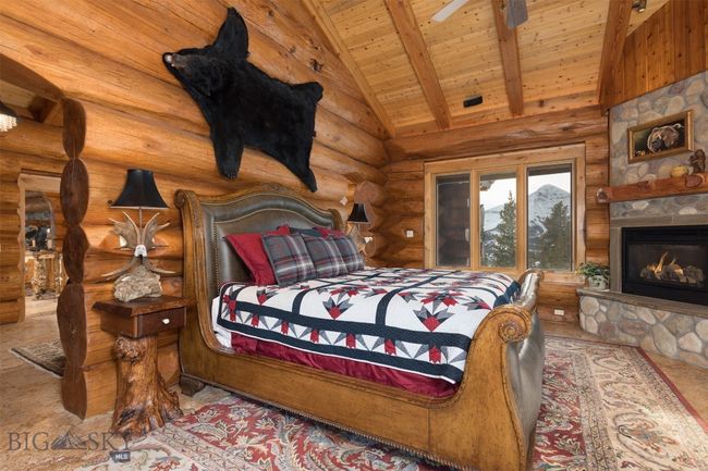 Main level primary bedroom with stone fireplace and vaulted ceiling. | Image 18