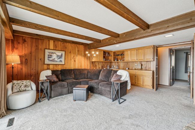 Lower level family room with elegant wood beams and a cozy wood burning stove | Image 26