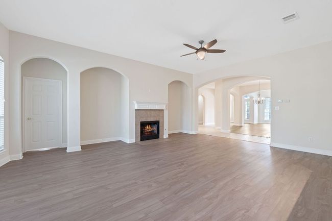 Unfurnished living room with visible vents, light wood-style flooring, a ceiling fan, and a tile fireplace | Image 18