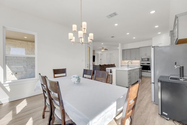 Dining space featuring recessed lighting, ceiling fan with notable chandelier, visible vents, baseboards, and light wood-style floors | Image 17
