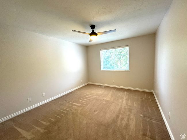 Main level bedroom featuring ceiling fan and large closet with organizer. | Image 18
