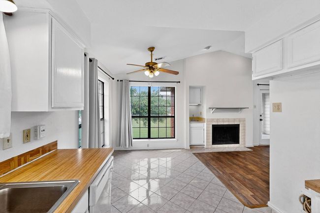 Kitchen featuring a ceiling fan, lofted ceiling, white cabinets, open floor plan, and white dishwasher | Image 12
