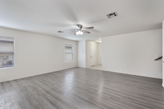 Unfurnished living room featuring ceiling fan, wood finished floors, and baseboards | Image 9