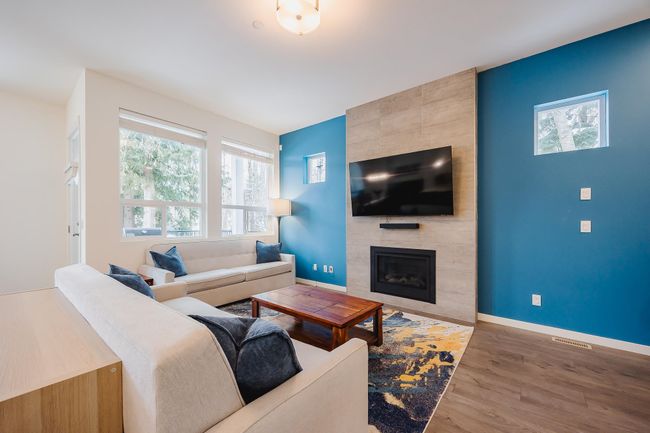 Living area with an accent wall, wood finished floors, a tile fireplace, and baseboards | Image 5