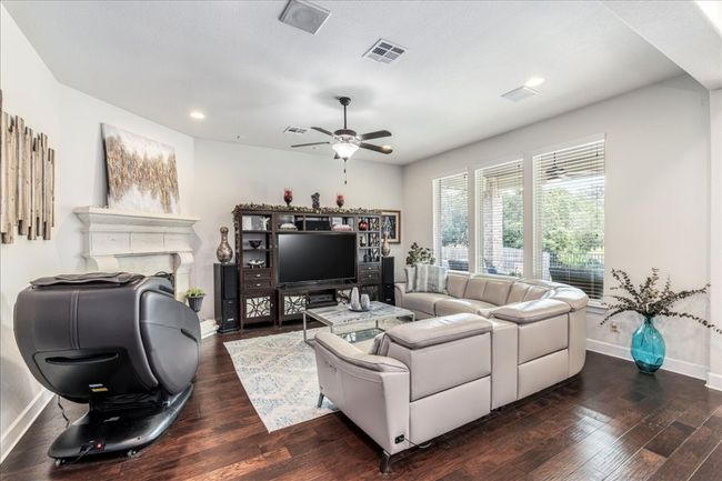 Living room with dark wood-type flooring, a fireplace, ceiling fan, and recessed lighting | Image 10