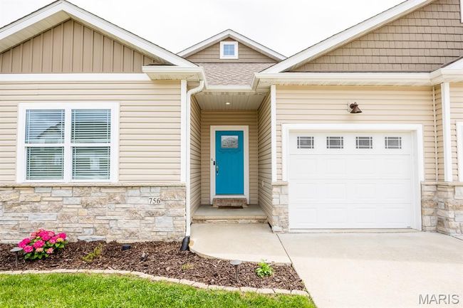 Entrance to property featuring stone siding, driveway, and a garage | Image 40