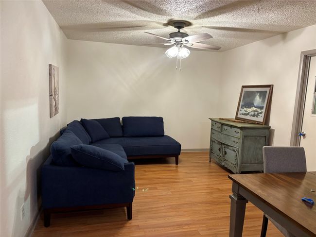 Den with light wood finished floors, a ceiling fan, and a textured ceiling | Image 11