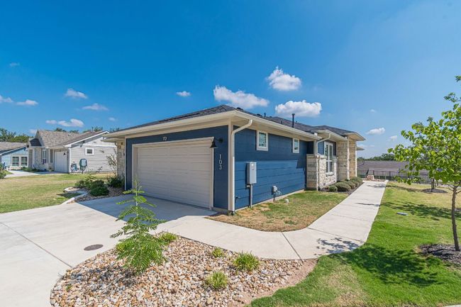 View of front of property featuring concrete driveway, a front yard, an attached garage, and stone siding | Image 35