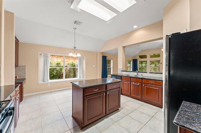 This spacious kitchen offers rich wood cabinetry, granite countertops, stainless steel appliances, and a gas cooktop. With a central island, wide prep areas, and an open layout, there’s plenty of room for more than one cook to move with ease. | Image 11