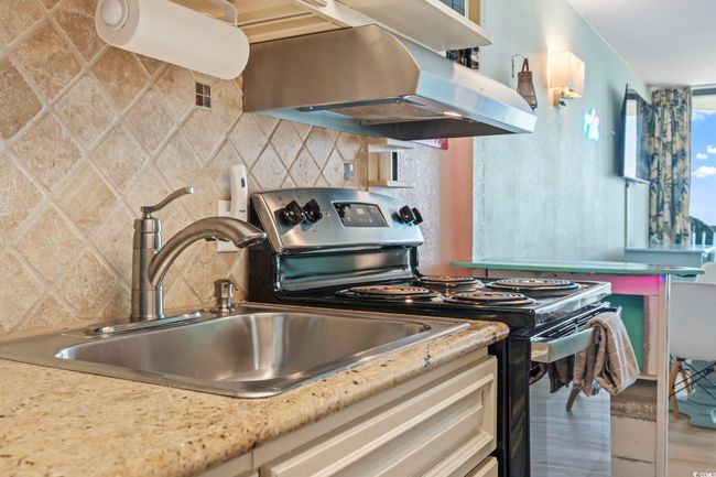 Kitchen featuring electric range, ventilation hood, tasteful backsplash, and wood finished floors | Image 10