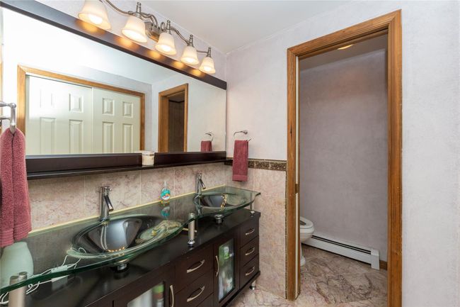 Primary Bathroom featuring double glass sinks, water closet with toilet and walk in shower and baseboard heating | Image 39