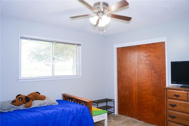Bedroom featuring a ceiling fan and light colored carpet | Image 13