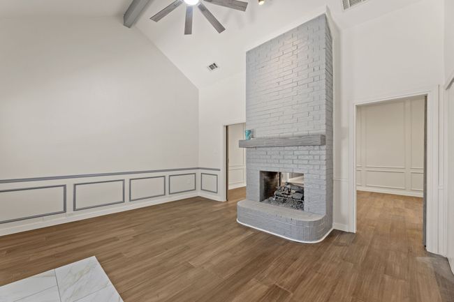 Unfurnished living room with ceiling fan, visible vents, a decorative wall, and beam ceiling | Image 18