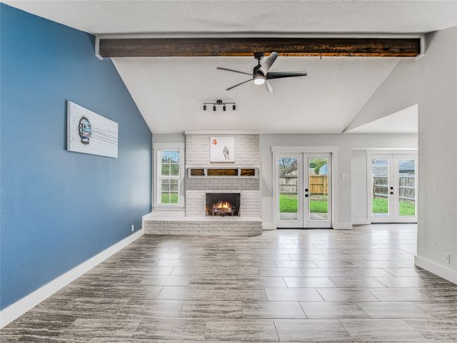 Unfurnished living room featuring baseboards, french doors, ceiling fan, and vaulted ceiling with beams | Image 5