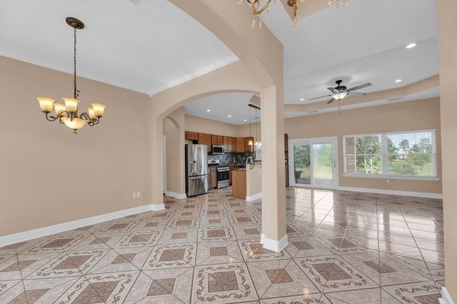 Kitchen featuring open floor plan, arched walkways, a chandelier, appliances with stainless steel finishes, and light tile patterned flooring | Image 13