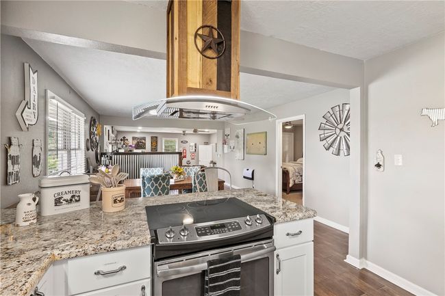 Kitchen with stainless steel electric range oven, dark wood-style flooring, healthy amount of natural light, white cabinetry, and a textured ceiling | Image 14