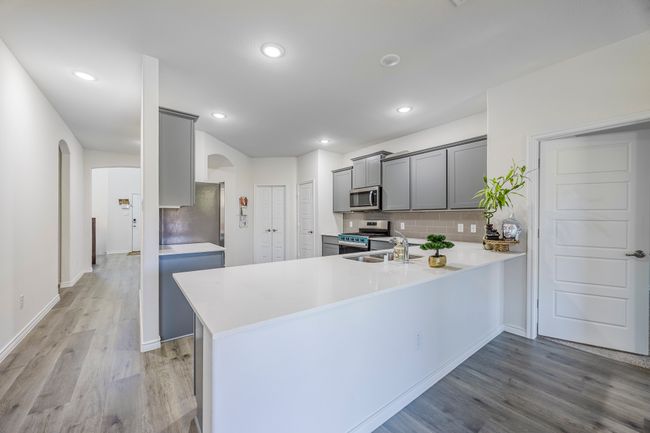Kitchen featuring stainless steel appliances, arched walkways, gray cabinets, light wood-style floors, and recessed lighting | Image 6