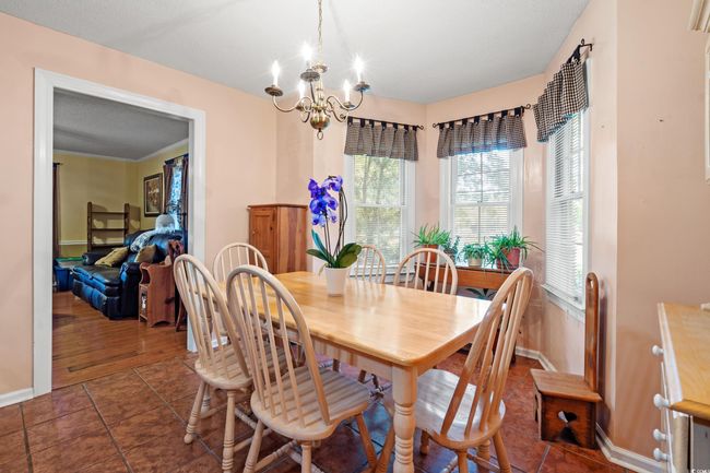 Dining area with a chandelier, baseboards, and dark tile patterned floors | Image 5