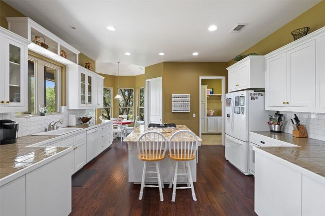 Kitchen with a center island, tasteful backsplash, a sink, white cabinets, and white appliances | Image 16
