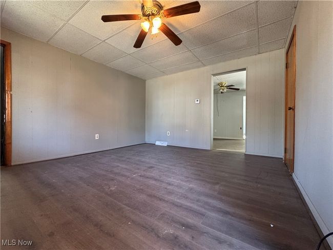 Unfurnished room featuring ceiling fan, visible vents, a drop ceiling, and wood finished floors | Image 23