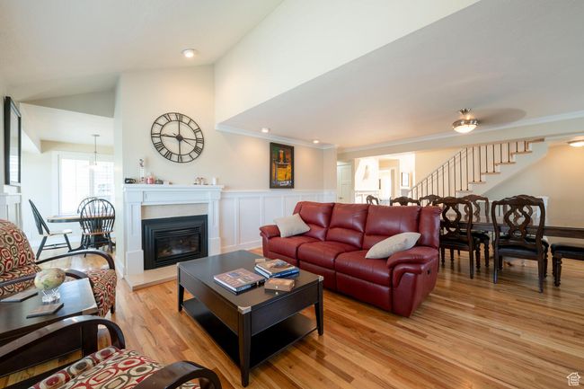 Living room featuring a glass covered fireplace, stairs, light wood-style flooring, and crown molding | Image 14