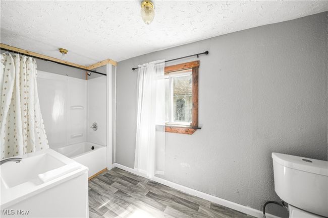 Full bath with baseboards, toilet, a textured ceiling, and shower / bathtub combination with curtain | Image 12