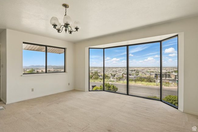 Carpeted spare room with a chandelier and baseboards | Image 5